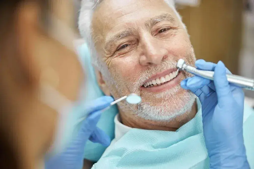 A dentist examining an older man's teeth during a check-up
