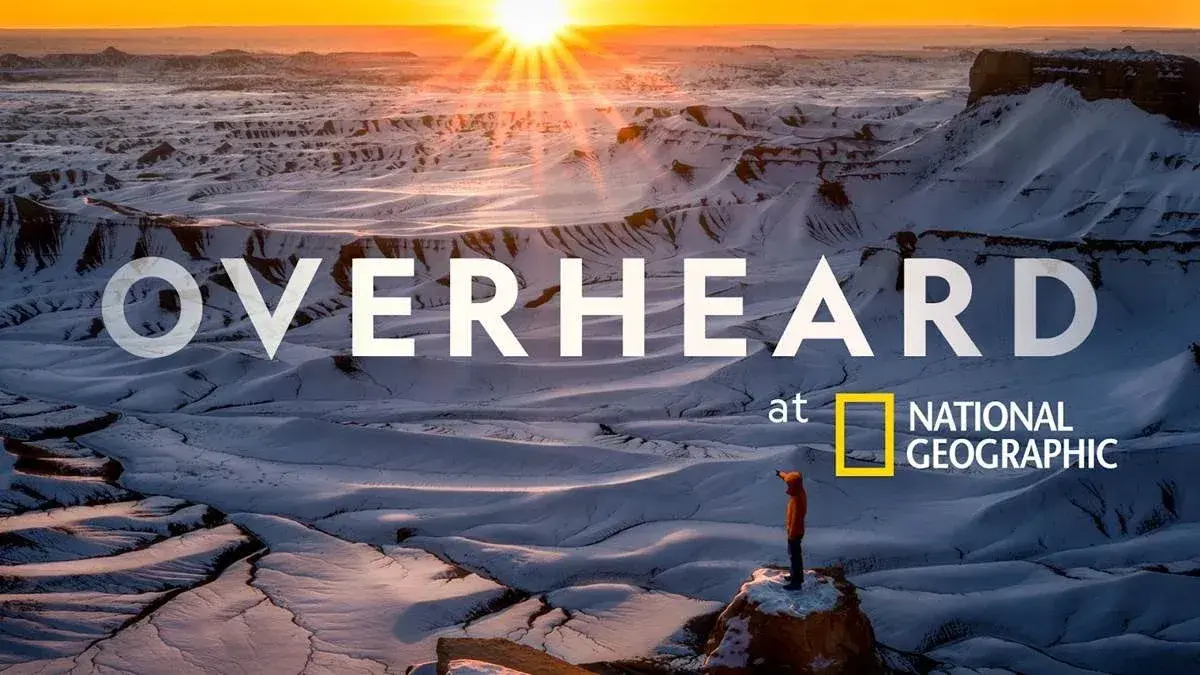 Title card for the National Geographic podcast Overheard, over a desert landscape at sunrise