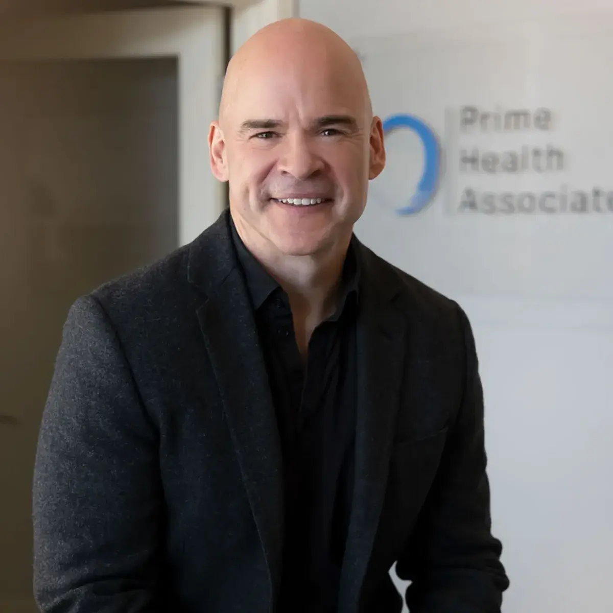 Dr. Kevin White standing in front of a Prime Health Associates sign