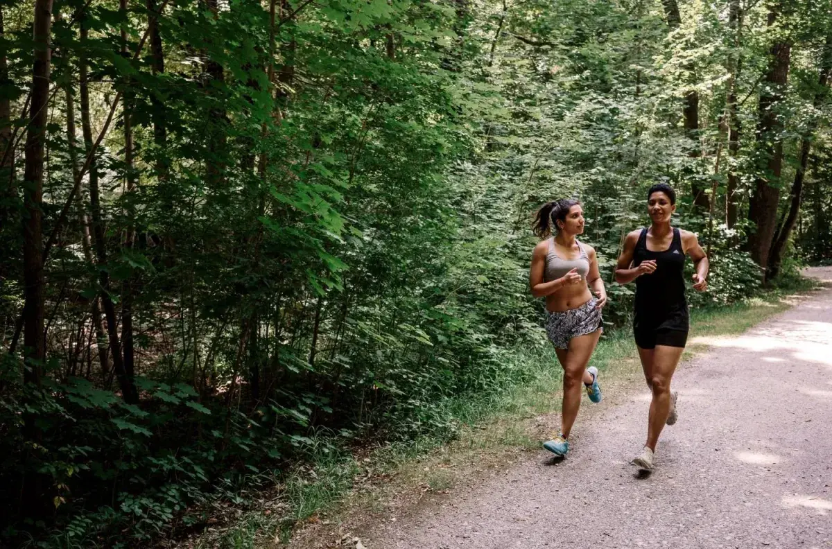 Two people running together along a wooded trail