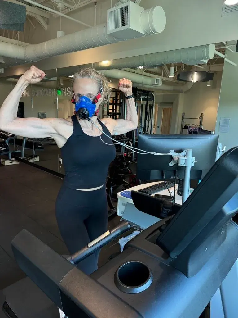 An Optispan team member flexing mid-test on a treadmill, wearing a metabolic mask and heart rate sensors