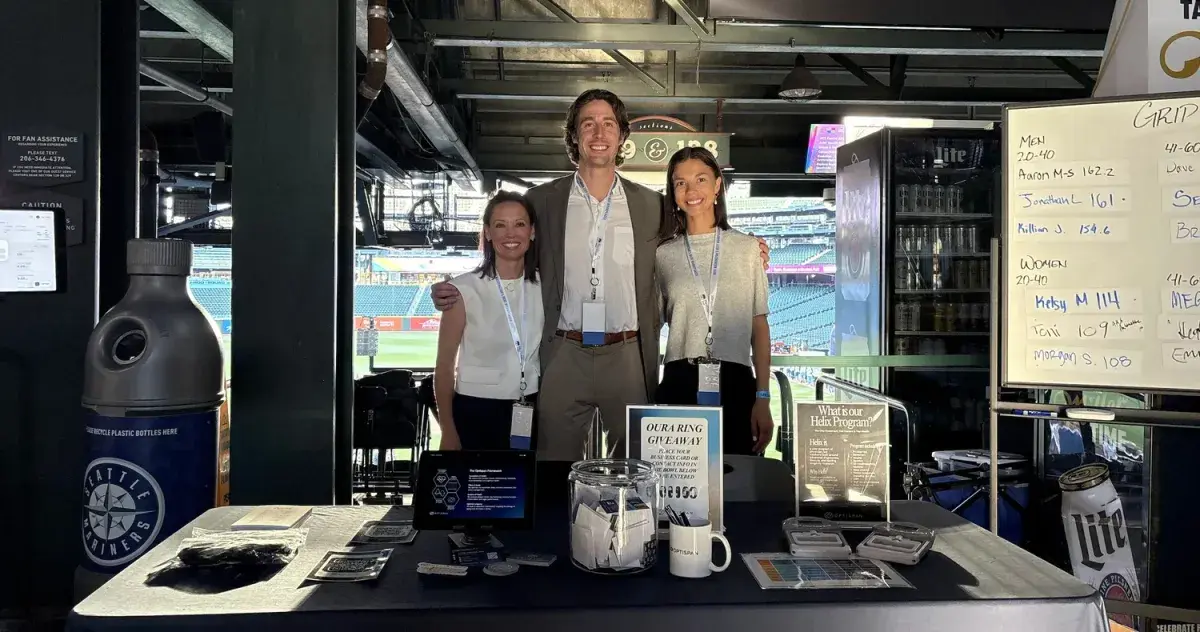 Three Optispan colleagues behind their booth at the ballpark, the field visible behind them